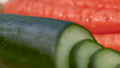 close-up of a cucumber being sliced alongside carrots, showcasing fresh, vibrant vegetables in a well-lit kitchen setting