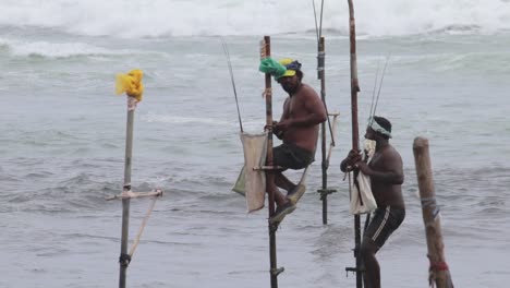 stilt fisherman getting ready to begin their day in the sea, beautiful waves crashing behind them as they climb to their poles
