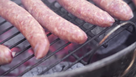 slow motion macro of sausages grilling on fiery and smokey bbq grill