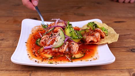 close-up of a plate of aguachile with avocado being served on a corn tostada