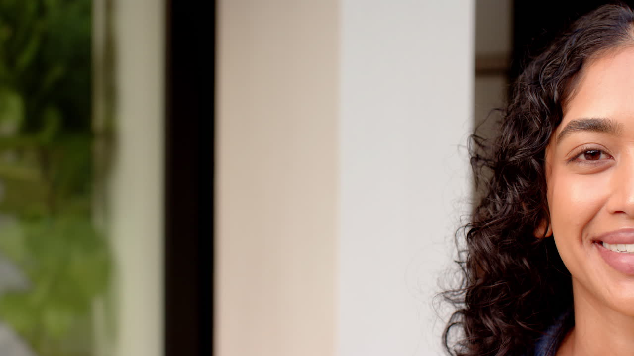 Smiling asian woman with curly hair enjoying time at home with friends, copy space