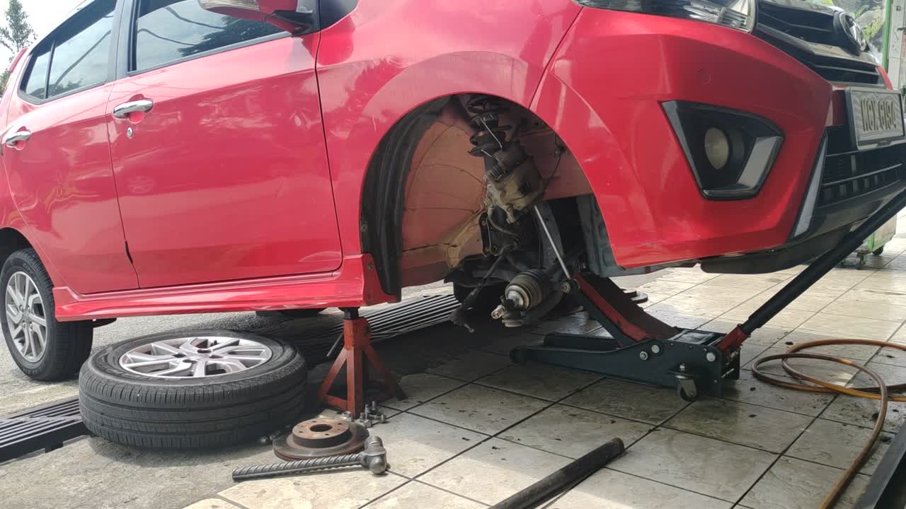 The car's exposed disk brake is ready for servicing at the workshop. The wheel has been removed for maintenance, ensuring optimal braking performance and safety.