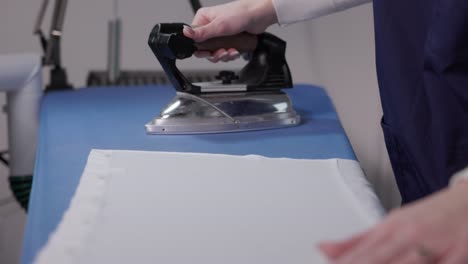 a woman's hand pressing clothing with an iron - close up