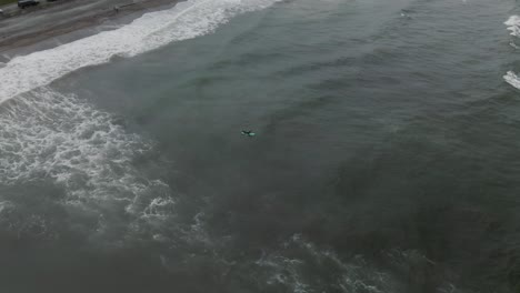 Surfer-Surfing-At-The-Perce-Coast-With-Foamy-Waves-Washing-Up-On-The-Beach-Shore-By-The-Gaspe-Peninsula-in-Quebec,-Canada