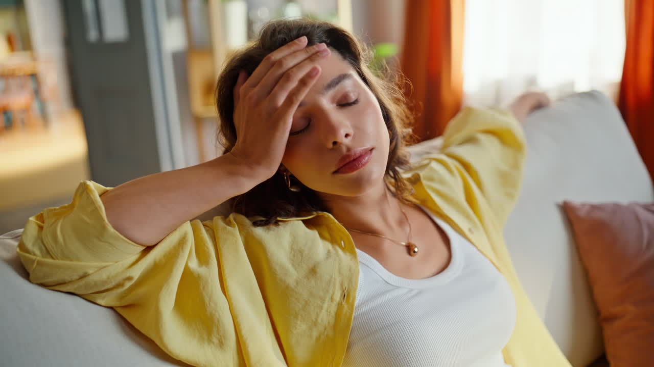 Primo piano di una donna seduta comodamente su un divano, stanca dopo una lunga giornata. Bruna rilassata