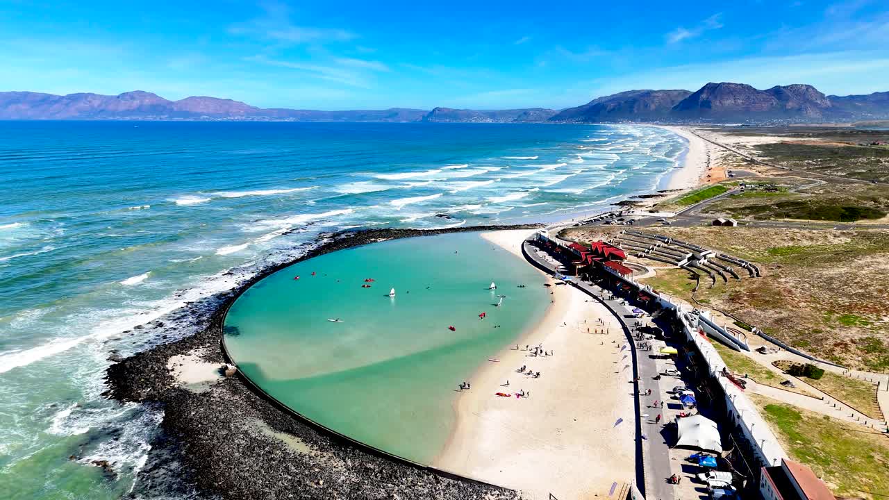 Cinematic clip of a coastal area in Cape Town South Africa with a popular tidal pool and beautiful scenic stretch of beach