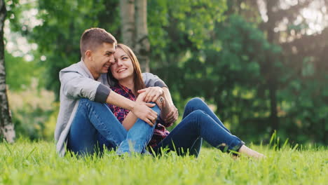 a couple in love resting in the park sitting in an embrace on the lawn talking hd video