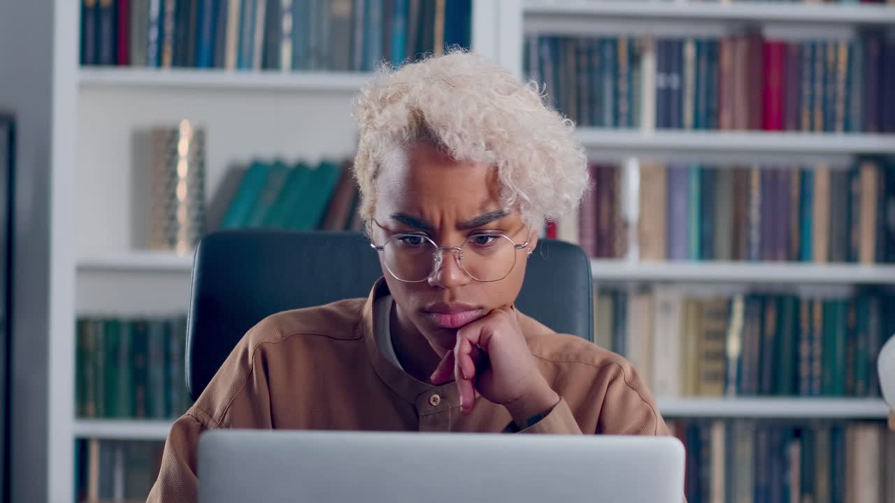 Primo piano di donna pensierosa e preoccupata che lavora al computer portatile, pensando a come risolvere un problema.