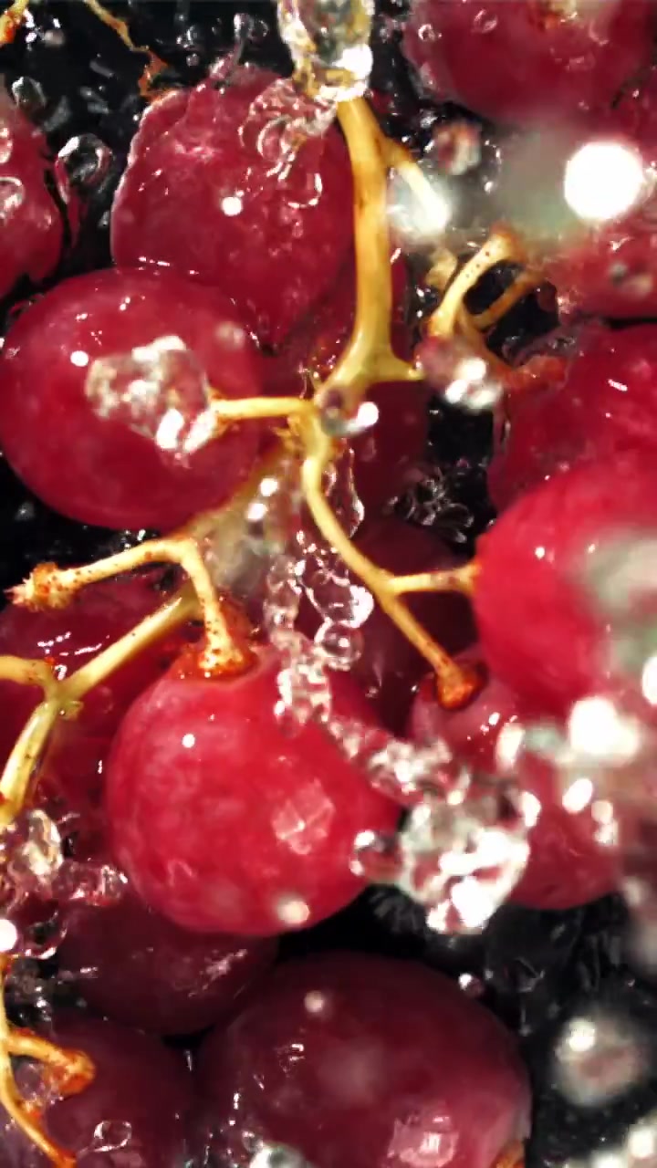 Agua salpicando uvas rojas vibrantes en cámara lenta