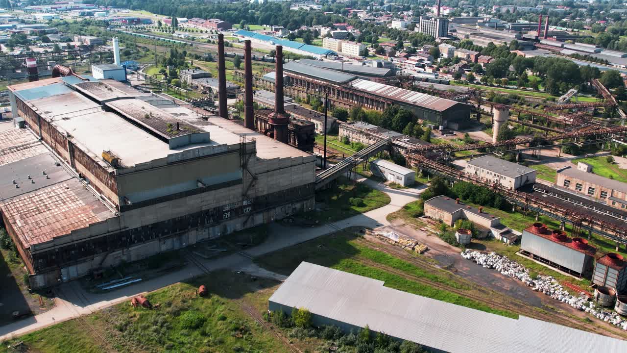 Vista aérea de un gran complejo fabril abandonado con almacenes, chimeneas, tuberías y edificios industriales. Antigua planta de fabricación pesada con una amplia infraestructura, que ilustra la etapa postindustrial
