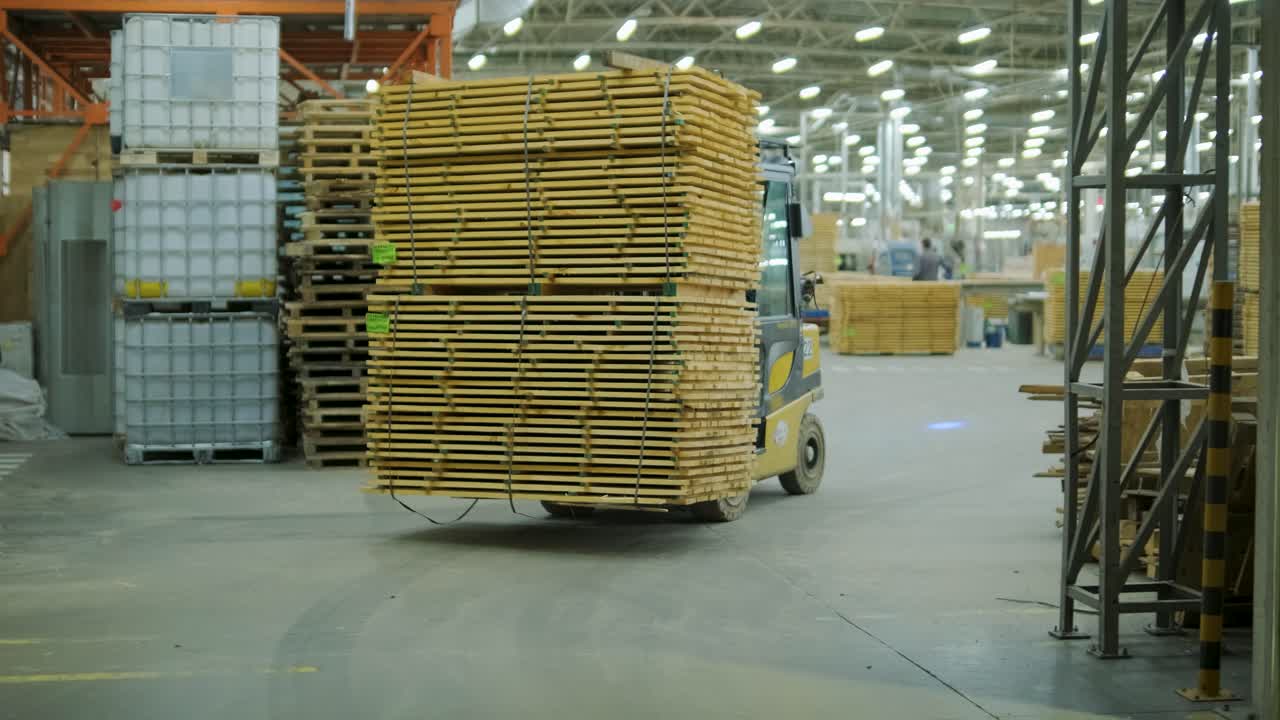 Gaffeltruck transporterer stabel af træplanker på et lager