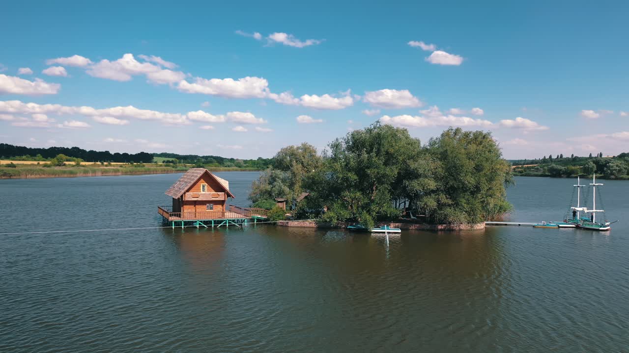 Green island and a house on water. Aerial view of beautiful island in the middle of a lake surrounded by water on the natural background.