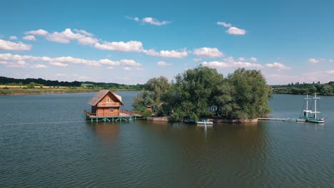 green island and a house on water. aerial view of beautiful island in the middle of a lake surrounded by water on the natural background.