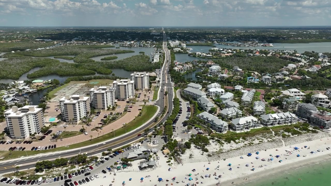 Flygfoto över Bonita Beach-bankvägen som slingrar sig genom mangroveträskens vattenvägar, med eleganta strandnära egendomar, palmer och Mexikanska golfen som skimrar i fjärran