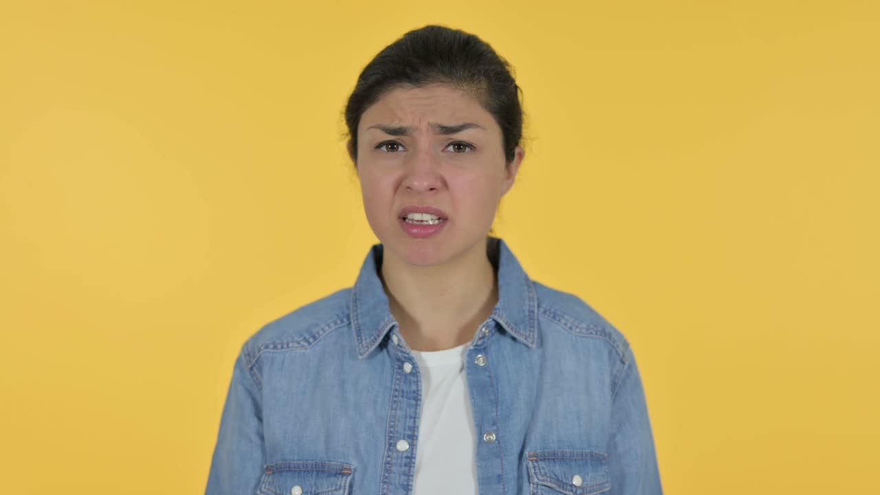 怒った若いインド人女性のビデオチャット - 黄色い背景