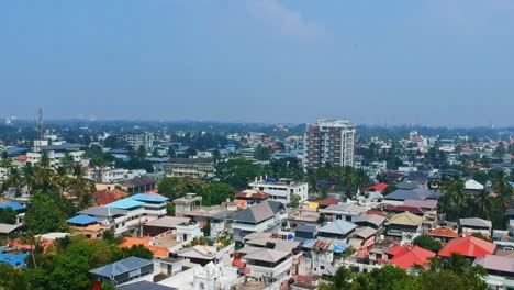 Vista-Aérea-De-Kochi,-Una-Ciudad-En-La-India,-Viviendas-Que-Consisten-En-Casas-Adosadas,-Tanques-Colocados-Encima-De-Las-Casas-Para-El-Suministro-De-Agua-Potable,-Un-Horizonte-De-Una-Ciudad-En-Crecimiento-Y-Una-Torre-Móvil