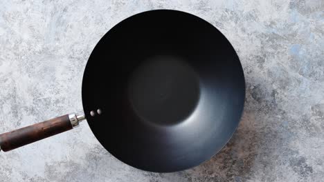 traditional empty black iron wok pan placed on stone background