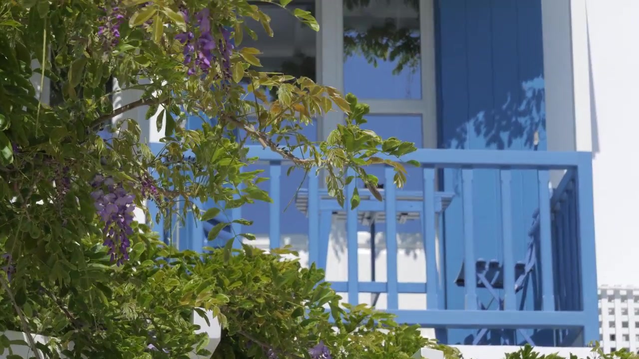 Pittoresco balcone blu e bianco di Mykonos con glicine viola in fiore in una splendida giornata di sole in Grecia.