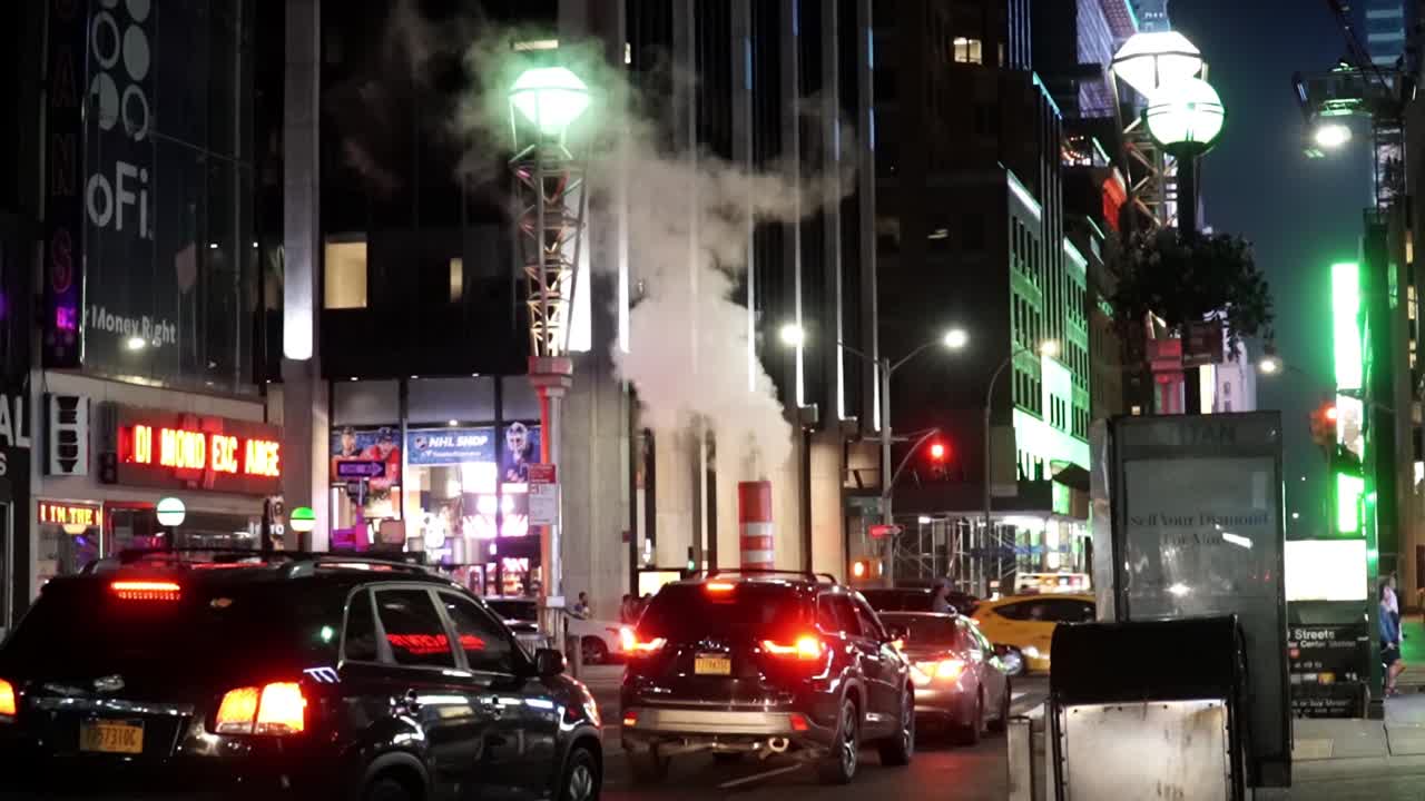 New York City Night Life Lights near Time Square. Iconic striped Steam Pipe releasing steam smoke in slow motion.