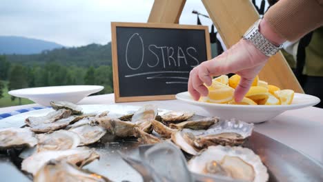 movimiento hacia atrás destapando la mano exprimiendo un limón encima de las ostras en un evento en galicia