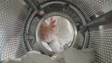 Woman-picks-up-washed-white-linen-from-washing-machine