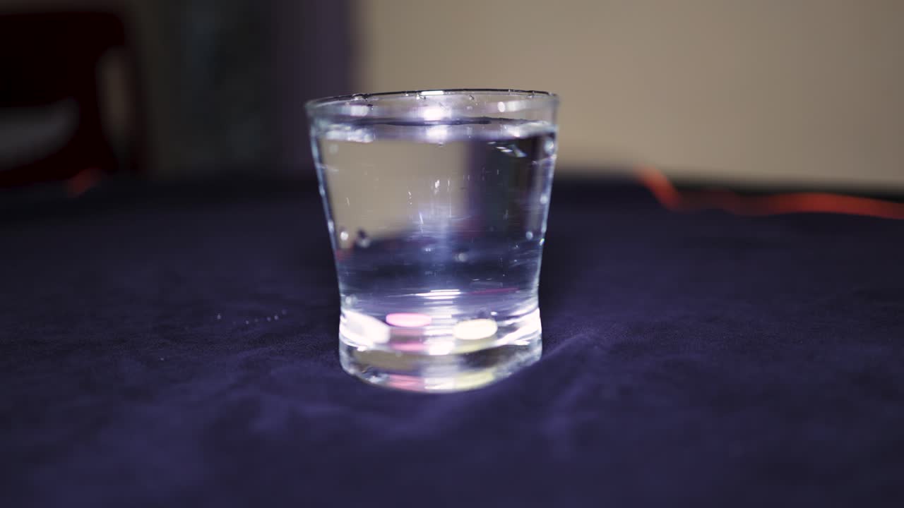water glass with pill dropping at indoor