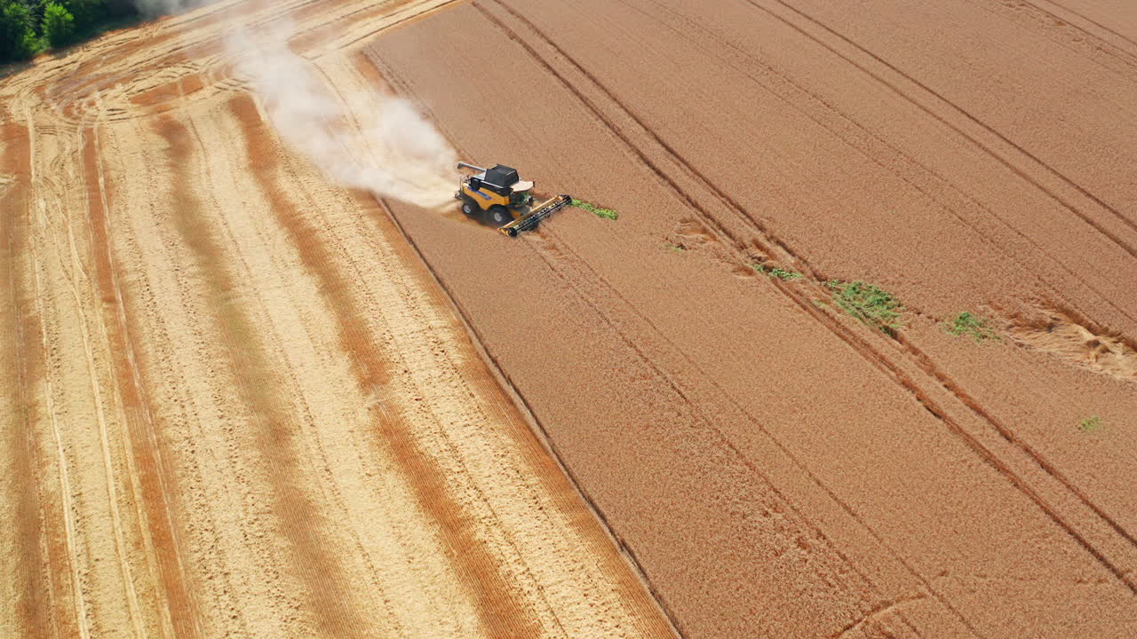 New yellow harvesting machine in the abundant farmland. Agricultural machine declined from a straight way and went diagonally in the field. Top view.