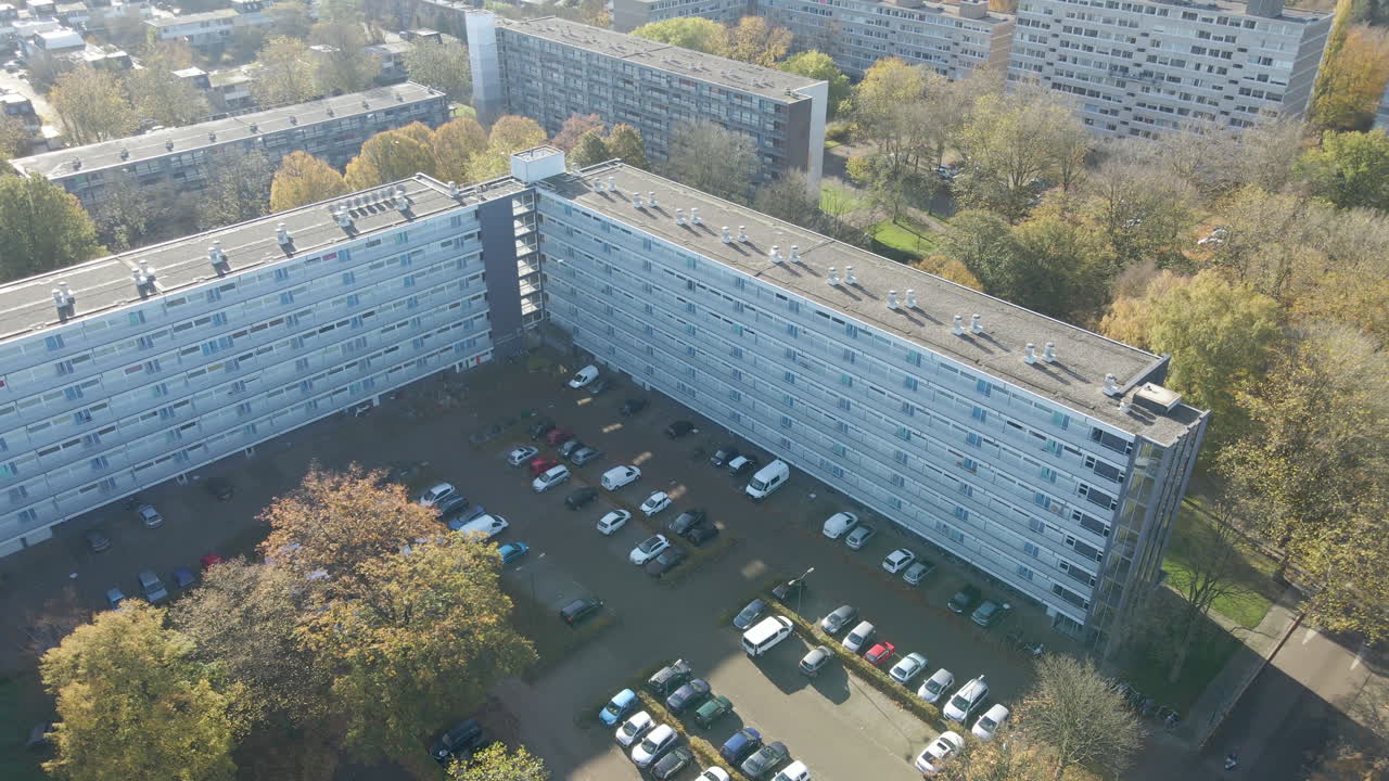 High jib up of social housing flat with busy parking lot in autumn