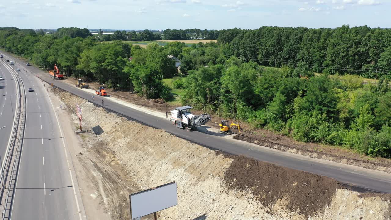 Roadworks of a new asphalt road. Modern machinery working on a road construction in summertime. Aerial view.