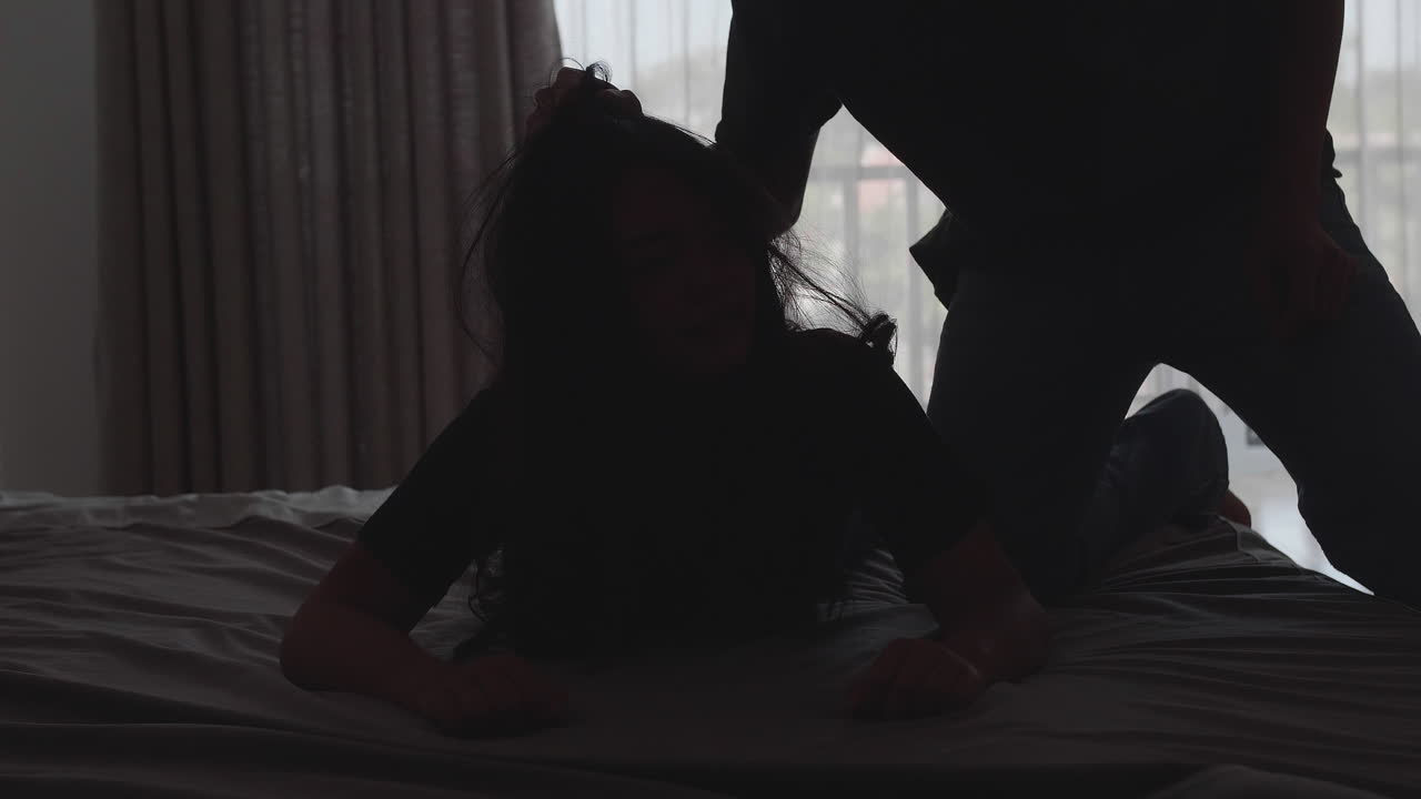 Silhouette Of Young Boyfriend Using Violence Against Girlfriend On The Bed
