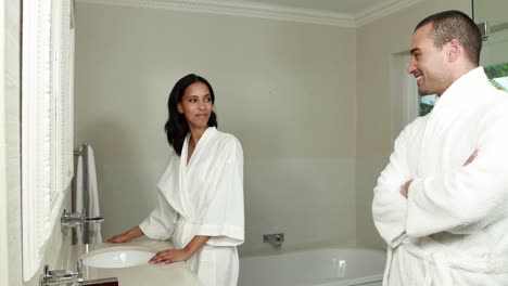 pareja sonriente discutiendo mientras usa bata de baño