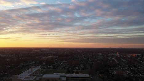 Una-Vista-De-Drones-De-Un-Barrio-De-Long-Island-Durante-Un-Amanecer-Dorado-Con-Nubes-Y-Cielos-Azules