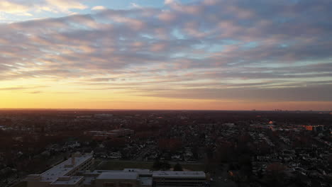 an drone view of a long island neighborhood during a golden sunrise with clouds and blue skies
