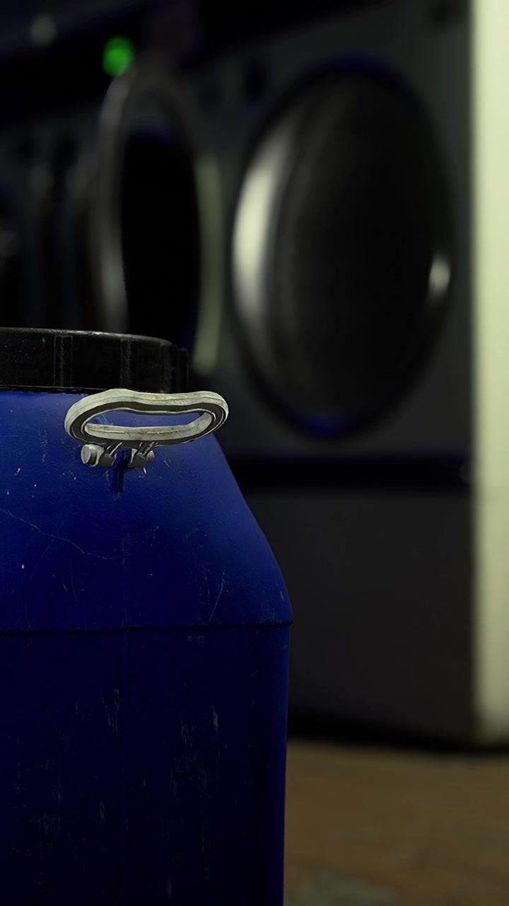 Un contenitore è posizionato su un tavolo con attrezzatura audio sullo sfondo.
