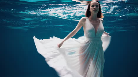 woman in a flowing white dress underwater