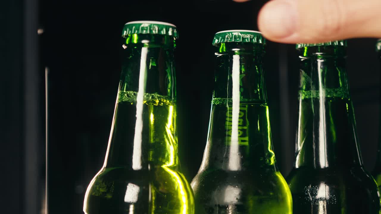 Row of beer bottles in fridge, shop or hotel, cold lager craft german beer or cider, shop supermarket or wine cooler close up.