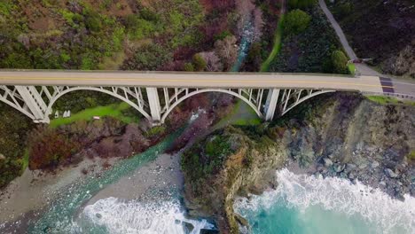 Overhead-aerial-view-of-Bixby-Creek-Bridge-and-crashing-ocean-waves-in-Big-Sur-on-State-Route-1-in-California
