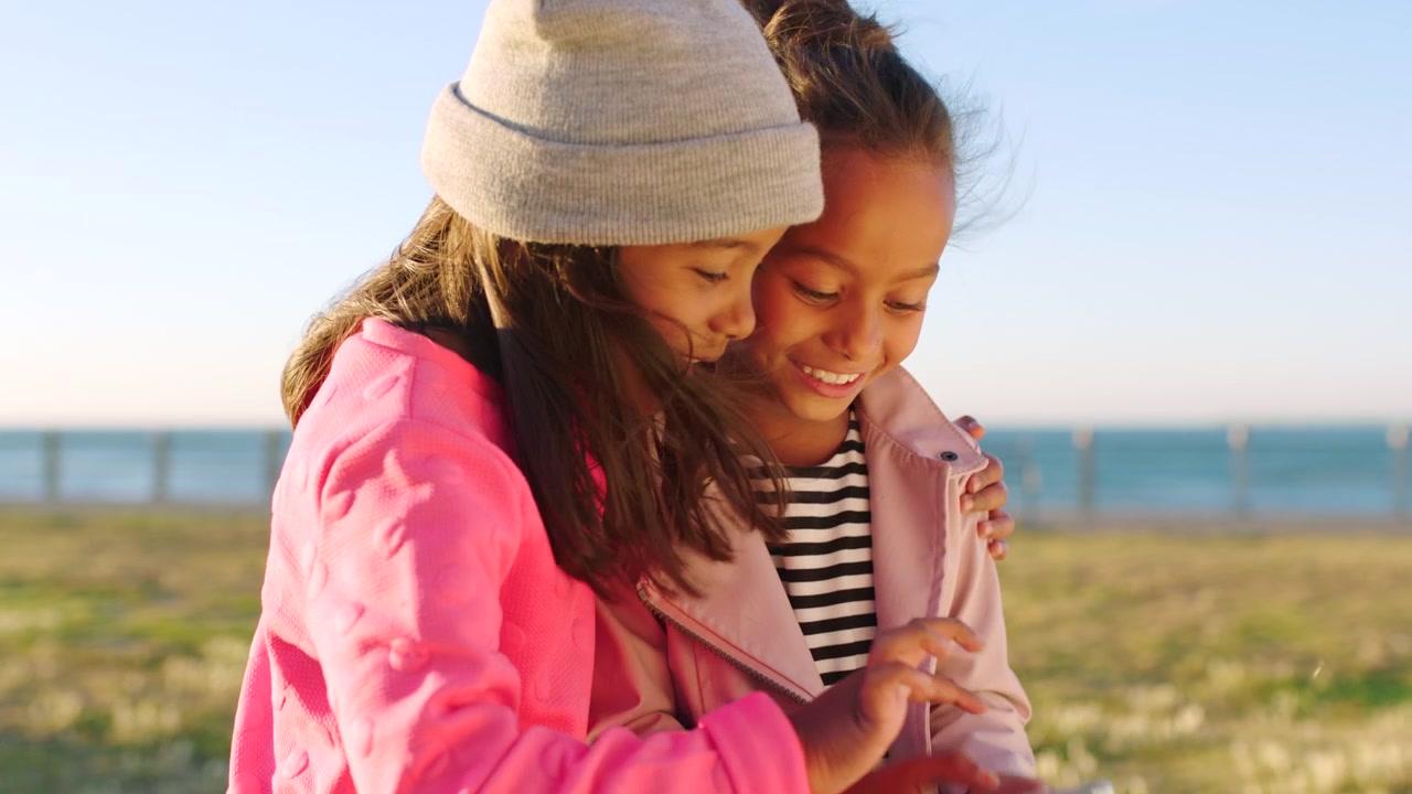 Two Young Girls Looking at a Smartphone Outdoors