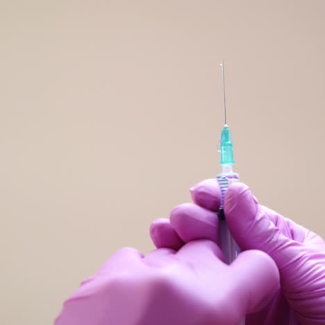 Close-up view on a cosmetologists hands in gloves holding syringe with needle for rejuvenating facial injections.