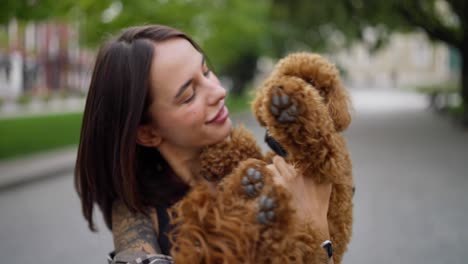 a woman holding a cute brown poodle in her arms, smiling