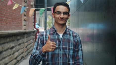 young man giving thumbs up in an alley
