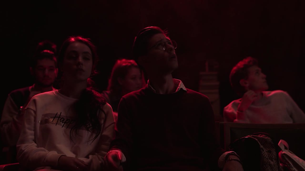 público viendo una actuación en una habitación débilmente iluminada