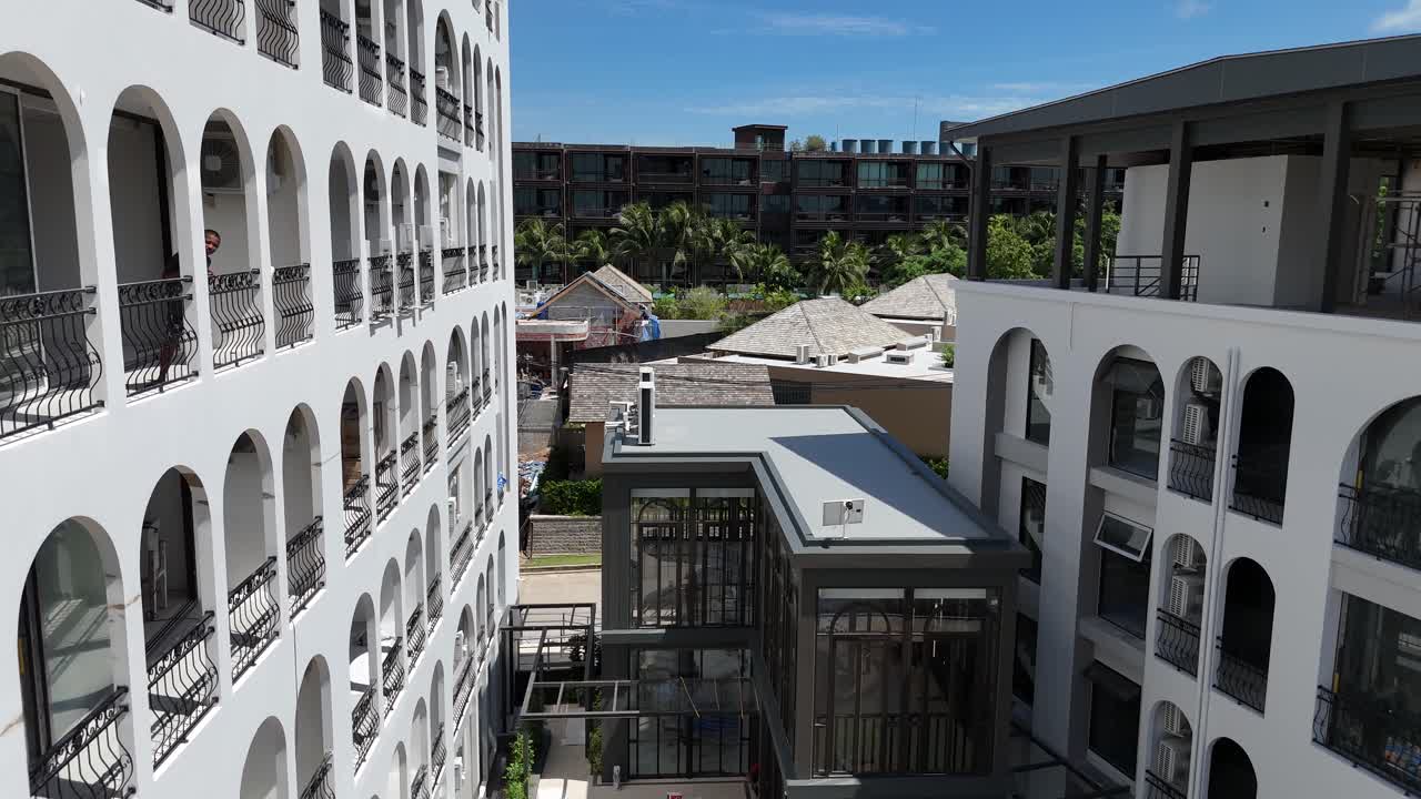 Modern Resort Buildings with Ongoing Construction and Palm Trees Under Blue Sky