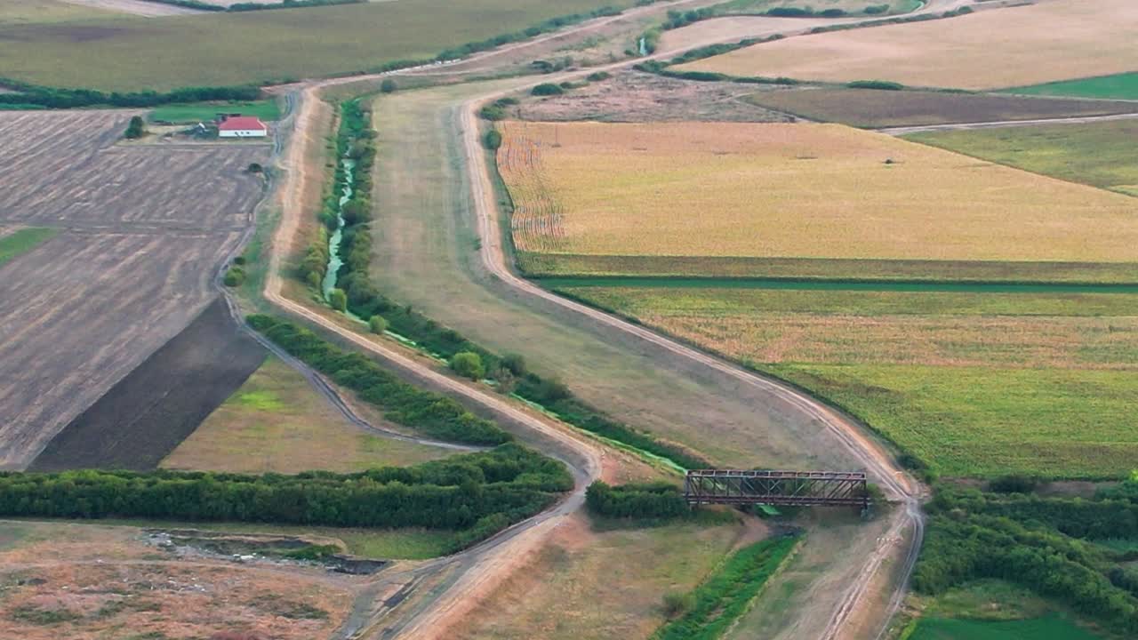 vuelo hacia atrás con zoom lento sobre tierras de cultivo con el puente a la vista