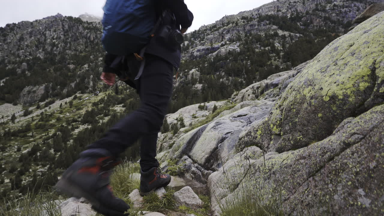 hiking high altitude mountains trekking path in Aig&uuml;estortes National Park solo male trekker carrying a backpack