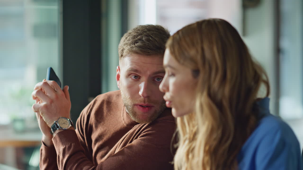 Serious coworker answering smartphone call in office coworking space closeup