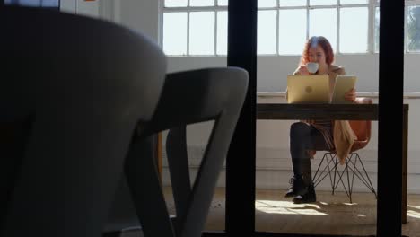 front view of young caucasian businesswoman working on digital tablet and laptop in a modern office