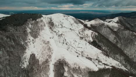 Winter-aerial-view-of-Cindrel-Mountains-with-snow-covered-peaks-and-forests