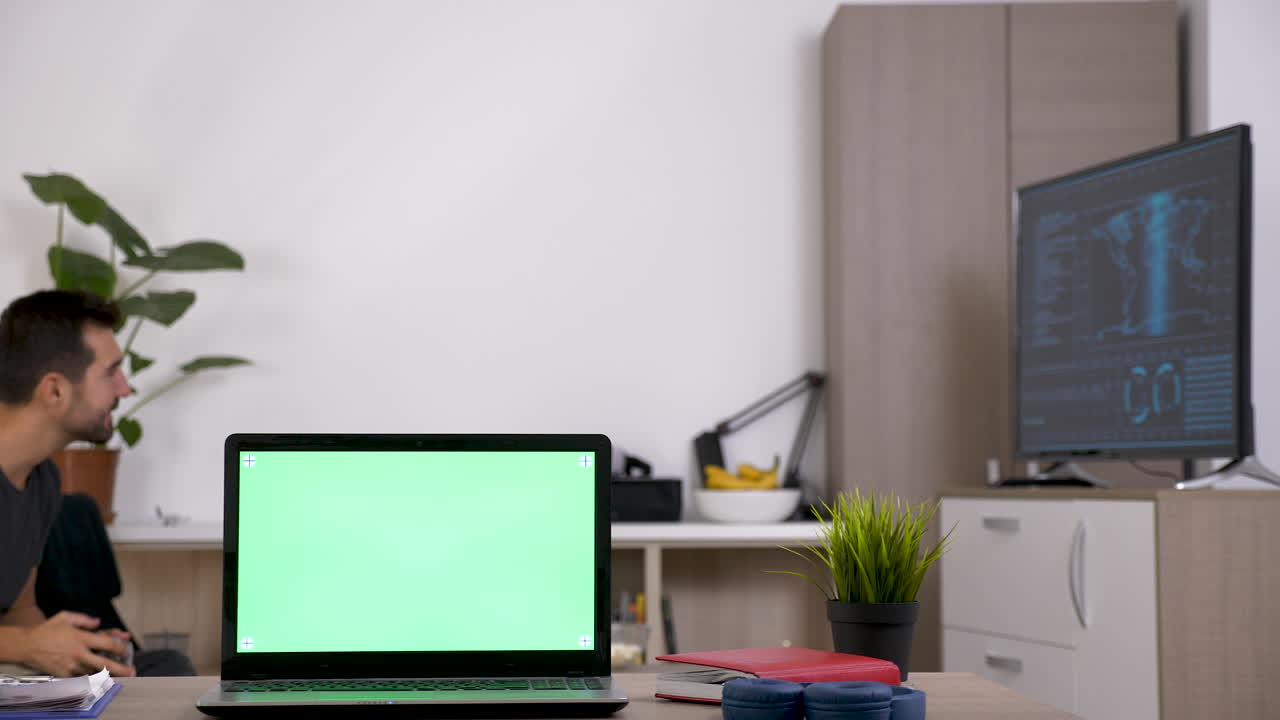 Laptop with green screen on a desk in a home office