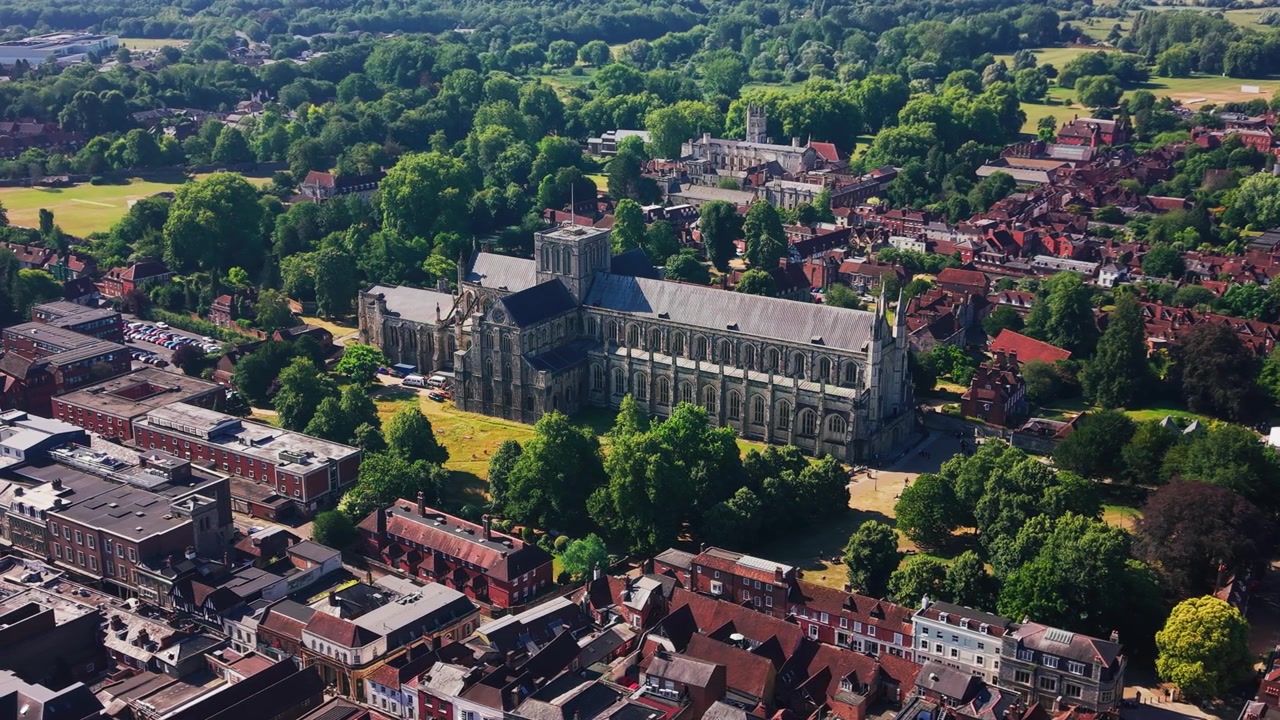 Vakre droneopptak fra luften av Winchester katedral omgitt av modne trær, historiske tak og bygninger i sentrum i Hampshire, England. Forhøyet utsikt som fremhever middelaldersk